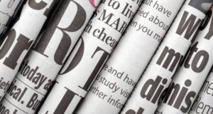 Newspaper headlines shown side on in a stack of daily newspapers.