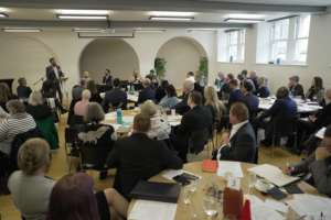 A photo of delegates attending the Scottish Government's anti-poverty summit, seated around circular tables listening to a speaker.